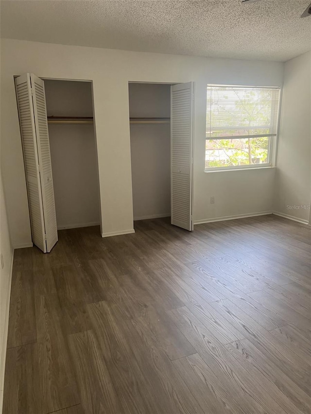 460 Sand Lime Rd, Winter Garden, FL 34787 - unfurnished bedroom with multiple closets, dark wood-type flooring, a textured ceiling, and baseboards