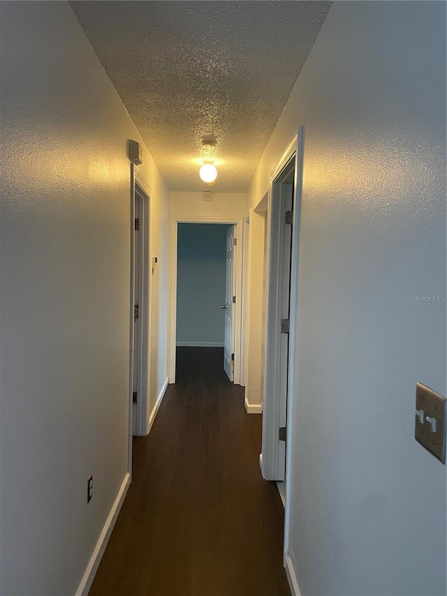 909 San Paulo Way, Kissimmee, FL 34758 - hallway with a textured ceiling, baseboards, and dark wood-style flooring