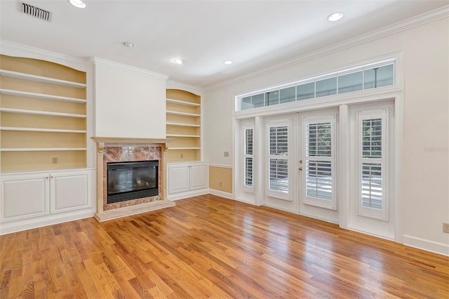 914 Elysium Blvd, Mount Dora, FL 32757 - unfurnished living room featuring ornamental molding, light wood-style flooring, a premium fireplace, built in features, and recessed lighting