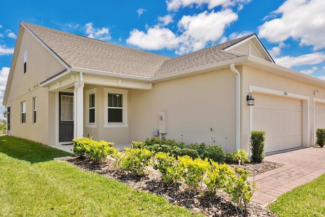 3280 Canna Lily Pl, Clermont, FL 34711 - view of side of property with stucco siding, an attached garage, a yard, roof with shingles, and driveway