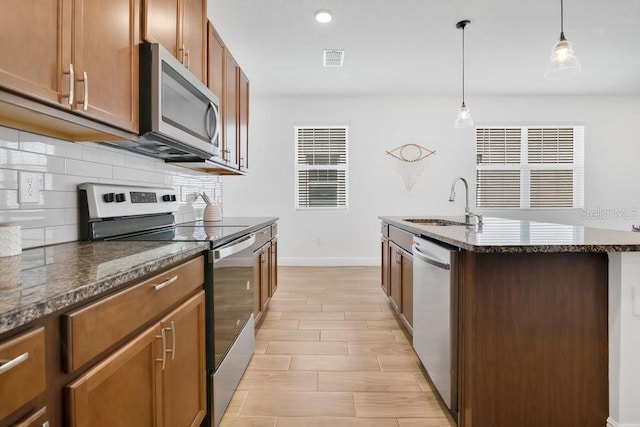 3280 Canna Lily Pl, Clermont, FL 34711 - kitchen featuring appliances with stainless steel finishes, a sink, decorative backsplash, dark stone counters, and baseboards