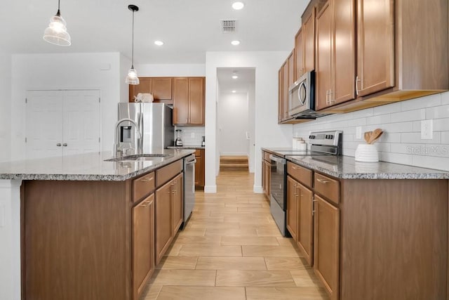 3280 Canna Lily Pl, Clermont, FL 34711 - kitchen with appliances with stainless steel finishes, backsplash, stone countertops, a sink, and an island with sink