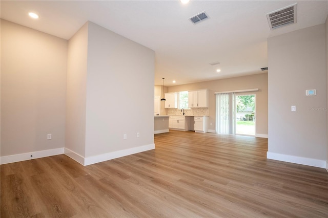 1331 19th St, Orlando, FL 32805 - unfurnished living room featuring light wood finished floors, recessed lighting, baseboards, and a sink