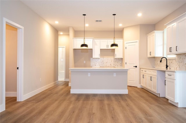 1331 19th St, Orlando, FL 32805 - kitchen featuring backsplash, a center island, light wood-style floors, white cabinetry, and recessed lighting