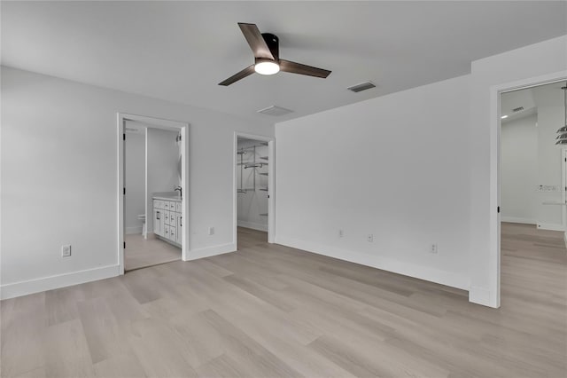 3461 W Webster Pl, Citrus Springs, FL 34433 - unfurnished bedroom with light wood-style flooring, baseboards, a spacious closet, ensuite bath, and a ceiling fan