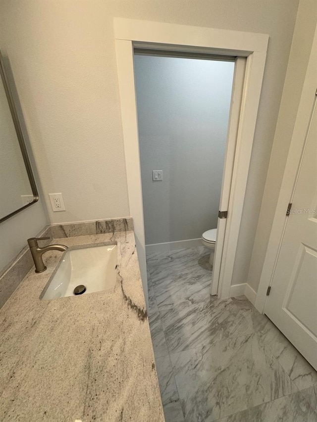 9 Bunker Pl, Rotonda West, FL 33947 - bathroom with marble look tiles, toilet, vanity, and baseboards