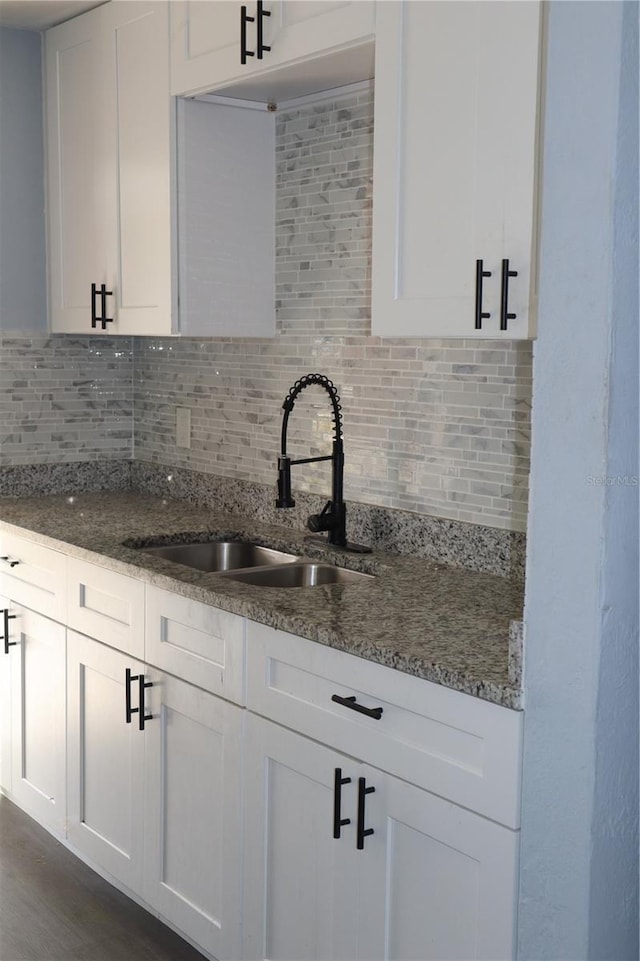 1212 Leon Ln, Daytona Beach, FL 32117 - kitchen with a sink, backsplash, white cabinetry, and dark stone counters