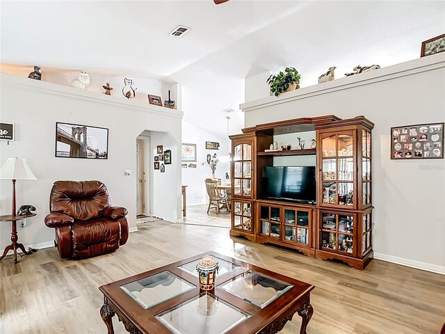 2771 NE 66th St, Ocala, FL 34479 - living area featuring arched walkways, light wood-type flooring, lofted ceiling, and baseboards