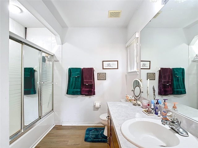 2771 NE 66th St, Ocala, FL 34479 - bathroom featuring wood finished floors, vanity, baseboards, toilet, and bath / shower combo with glass door