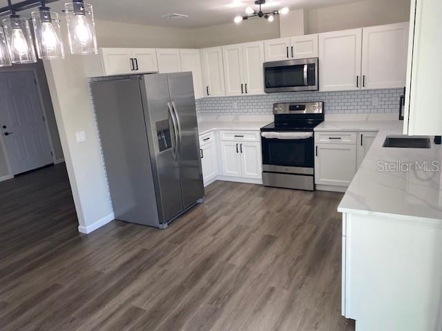 1750 Mitten Ter, Deltona, FL 32738 - kitchen featuring stainless steel appliances, dark wood finished floors, tasteful backsplash, white cabinetry, and a chandelier