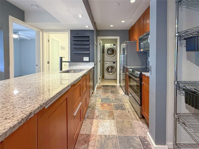 3034 Parkway Blvd Unit 102, Kissimmee, FL 34747 - kitchen with a sink, stainless steel appliances, stacked washer and clothes dryer, brown cabinetry, and stone tile floors