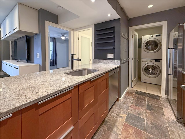 3034 Parkway Blvd Unit 102, Kissimmee, FL 34747 - kitchen featuring stacked washer / dryer, a sink, stainless steel dishwasher, ceiling fan, and brown cabinetry