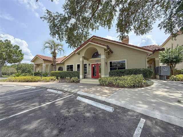 3034 Parkway Blvd Unit 102, Kissimmee, FL 34747 - view of front of property with a chimney, a tiled roof, stucco siding, uncovered parking, and french doors