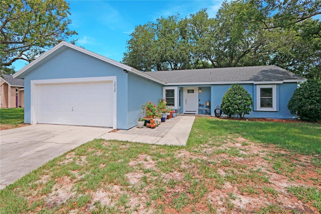 5032 Timber Ridge Trl, Ocoee, FL 34761 - ranch-style house with a garage, stucco siding, driveway, a front yard, and roof with shingles