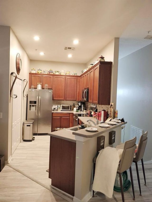 725 Ashworth Overlook Dr Unit C, Apopka, FL 32712 - kitchen featuring stainless steel appliances, light wood-style flooring, a peninsula, baseboards, and decorative backsplash