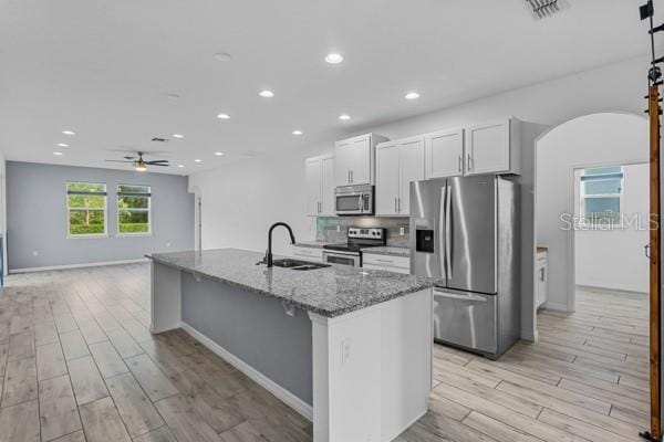 2914 Scarlett Dr, Saint Cloud, FL 34772 - kitchen featuring appliances with stainless steel finishes, a sink, ceiling fan, light wood-style flooring, and white cabinets