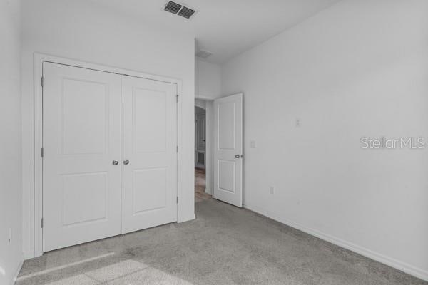 2914 Scarlett Dr, Saint Cloud, FL 34772 - unfurnished bedroom featuring carpet flooring, a closet, and baseboards