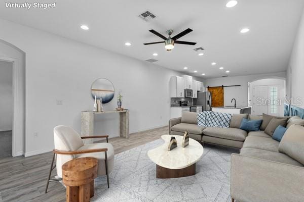 2914 Scarlett Dr, Saint Cloud, FL 34772 - living room with arched walkways, a ceiling fan, light wood-style floors, recessed lighting, and baseboards
