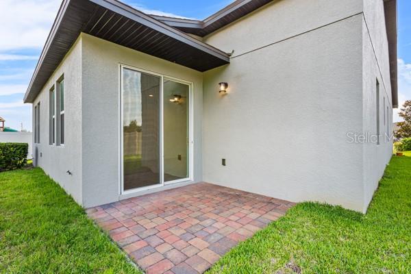 2914 Scarlett Dr, Saint Cloud, FL 34772 - rear view of property featuring stucco siding, a patio area, and a lawn