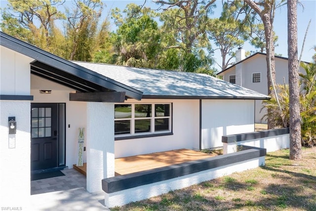back of property with stucco siding and a shingled roof