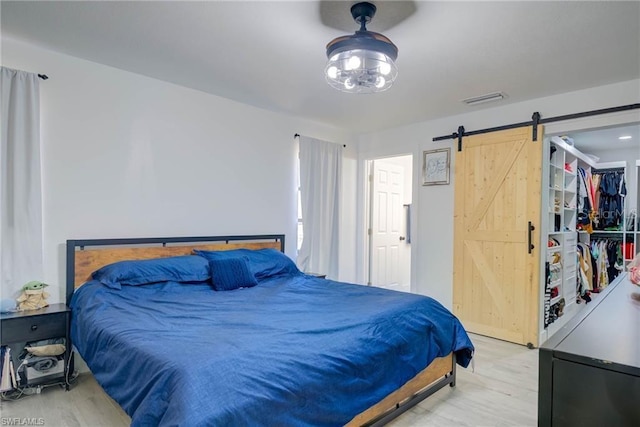 bedroom featuring wood finished floors, a barn door, and a spacious closet