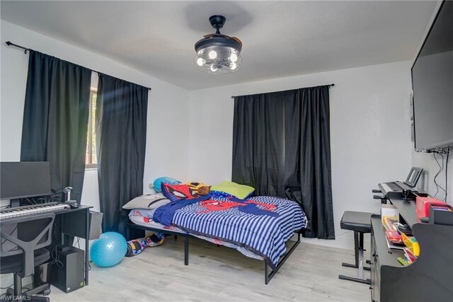 bedroom with light wood-type flooring and a desk