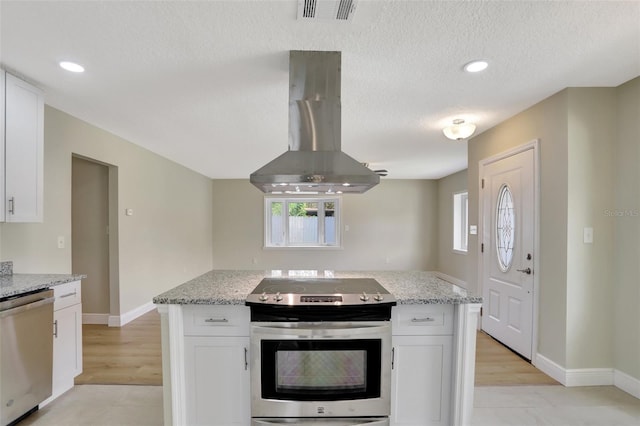 2835 Bongart Rd, Winter Park, FL 32792 - kitchen with stainless steel appliances, island range hood, white cabinetry, a textured ceiling, and baseboards