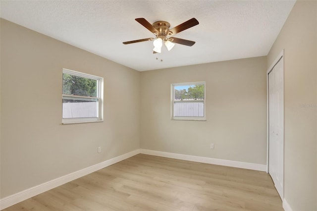 2835 Bongart Rd, Winter Park, FL 32792 - unfurnished bedroom featuring multiple windows, light wood-style flooring, baseboards, a closet, and a textured ceiling