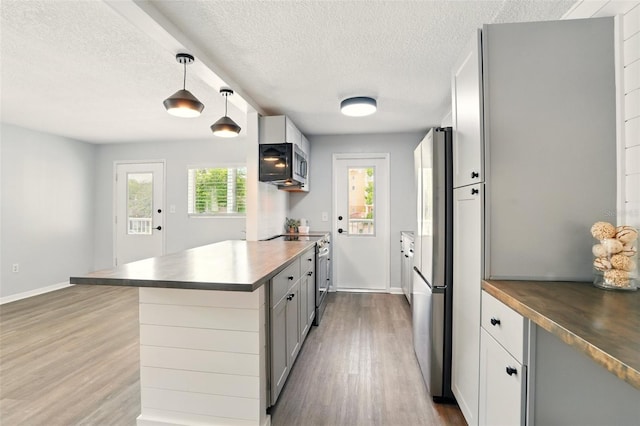 320 Lakeview St Unit 220, Orlando, FL 32804 - kitchen with stainless steel appliances, wood finished floors, a peninsula, baseboards, and a textured ceiling