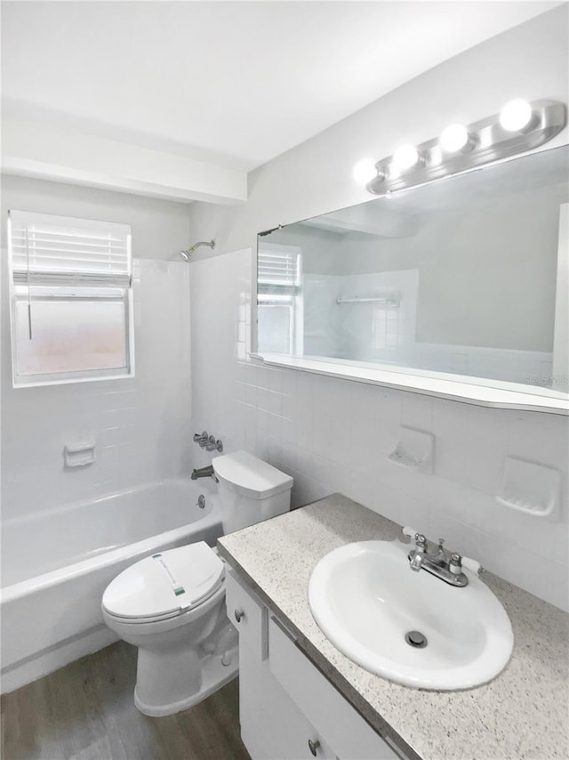 7604 Tyson Dr, Port Richey, FL 34668 - full bath featuring  shower combination, toilet, vanity, wood finished floors, and tile walls