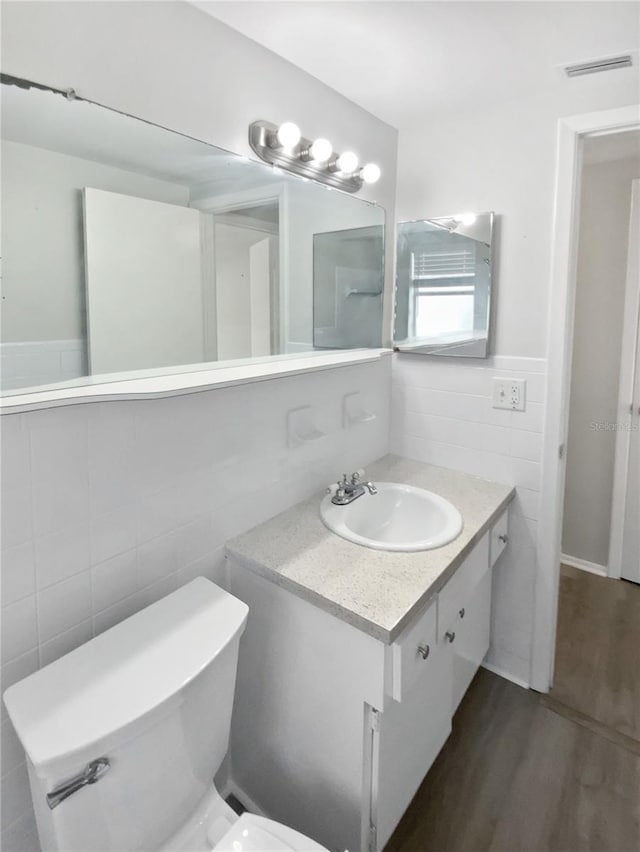 7604 Tyson Dr, Port Richey, FL 34668 - bathroom with tile walls, vanity, wood finished floors, toilet, and a wainscoted wall