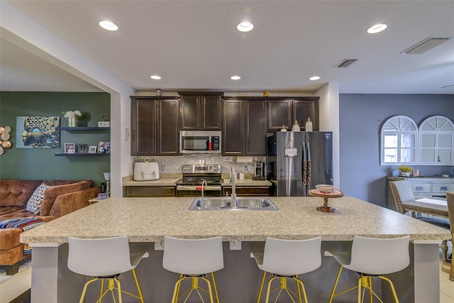 322 Annabelle Way, Davenport, FL 33837 - kitchen featuring stainless steel appliances, dark brown cabinets, light countertops, an island with sink, and recessed lighting