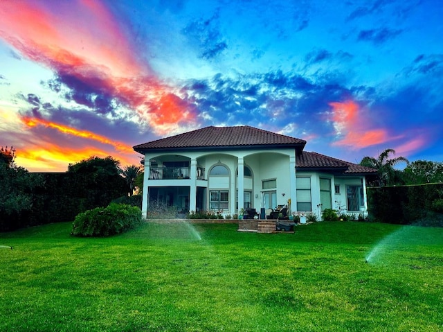1010 Juliette Blvd, Mount Dora, FL 32757 - back of property at dusk featuring a tile roof, a lawn, and stucco siding