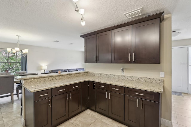 8652 Savory Dr, Orlando, FL 32825 - kitchen with a chandelier, a peninsula, light tile patterned floors, dark brown cabinets, and a textured ceiling