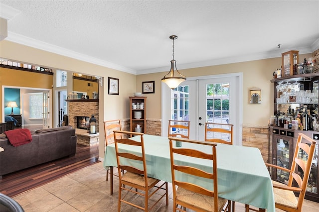 556 Lake Ave, Altamonte Springs, FL 32701 - dining space featuring french doors, ornamental molding, a stone fireplace, light tile patterned floors, and a textured ceiling