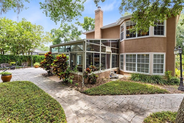 556 Lake Ave, Altamonte Springs, FL 32701 - rear view of property with a sunroom, stucco siding, a chimney, and a patio area