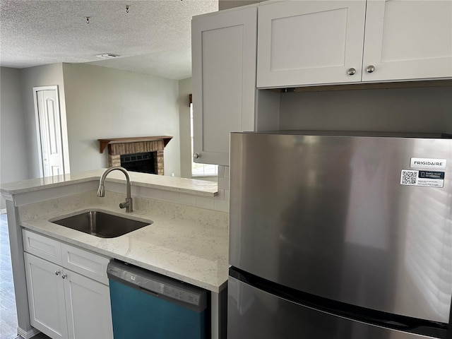652 Roaring Dr Unit 234, Altamonte Springs, FL 32714 - kitchen with dishwasher, freestanding refrigerator, a sink, a fireplace, and light stone countertops