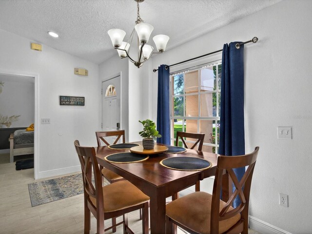 703 Sunridge Woods Blvd, Davenport, FL 33837 - dining area featuring a textured ceiling, baseboards, a chandelier, and light wood finished floors