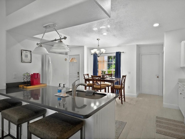 703 Sunridge Woods Blvd, Davenport, FL 33837 - kitchen with white refrigerator, a sink, a chandelier, baseboards, and a kitchen breakfast bar