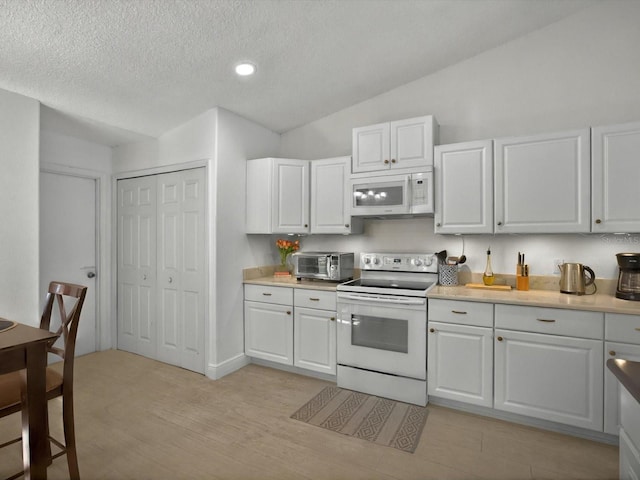 703 Sunridge Woods Blvd, Davenport, FL 33837 - kitchen featuring white appliances, light countertops, white cabinets, a textured ceiling, and vaulted ceiling
