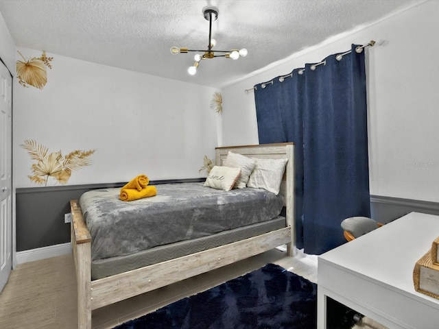 703 Sunridge Woods Blvd, Davenport, FL 33837 - bedroom featuring a chandelier, wood finished floors, a textured ceiling, and baseboards