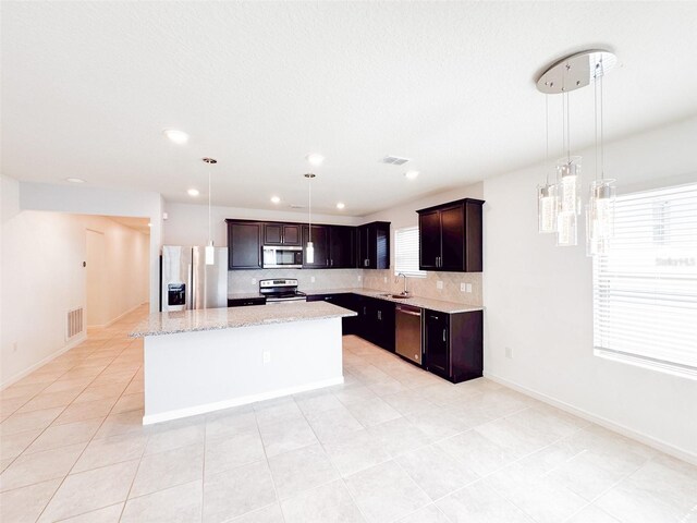 398 Citrus Isle Loop, Davenport, FL 33837 - kitchen featuring stainless steel appliances, a sink, backsplash, a center island, and light tile patterned floors