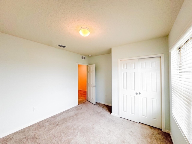 398 Citrus Isle Loop, Davenport, FL 33837 - unfurnished bedroom featuring light carpet, a closet, baseboards, and a textured ceiling
