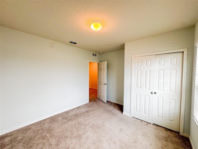 398 Citrus Isle Loop, Davenport, FL 33837 - unfurnished bedroom featuring light colored carpet, a closet, baseboards, and a textured ceiling