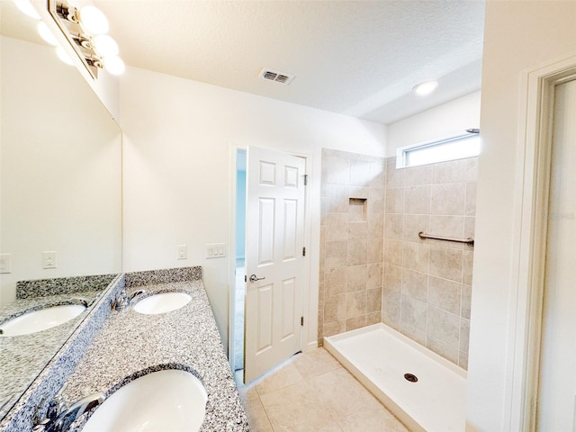 398 Citrus Isle Loop, Davenport, FL 33837 - bathroom featuring double vanity, tile patterned flooring, tiled shower, and a textured ceiling