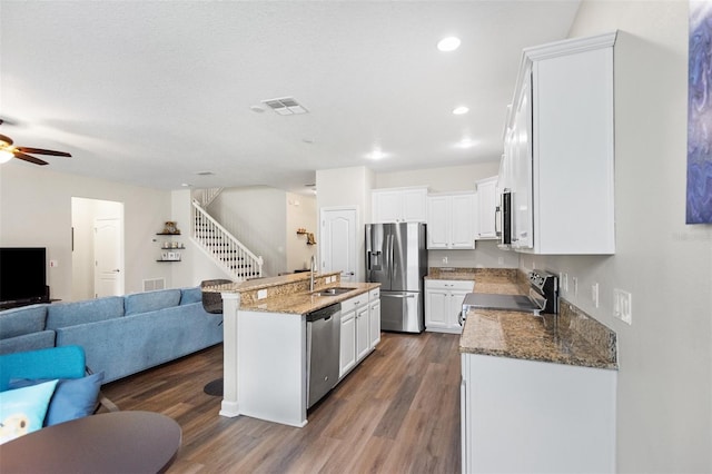 6333 Schoolhouse Pond Rd, Winter Garden, FL 34787 - kitchen featuring appliances with stainless steel finishes, open floor plan, a sink, dark wood-style floors, and dark stone countertops
