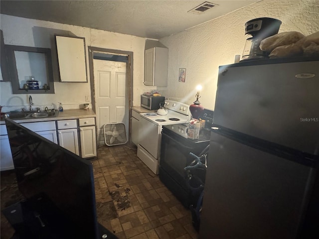 1500 43rd St, Orlando, FL 32839 - kitchen featuring freestanding refrigerator, white range with electric stovetop, a textured wall, stainless steel microwave, and a textured ceiling
