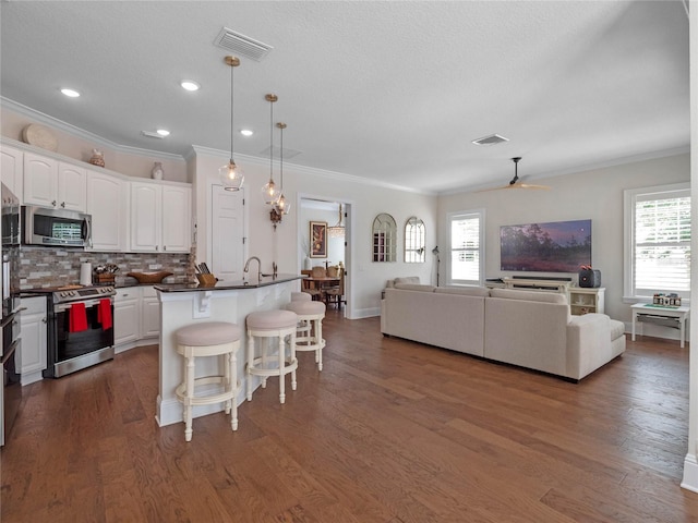 1438 Stickley Ave, Celebration, FL 34747 - kitchen featuring stainless steel appliances, a breakfast bar, dark countertops, white cabinetry, and open floor plan