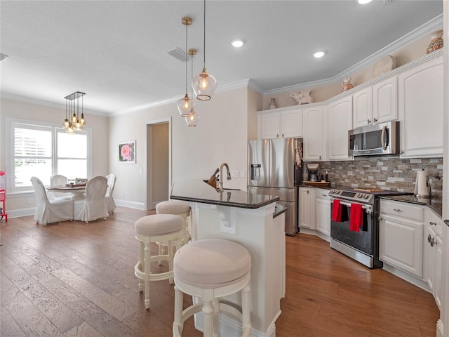 1438 Stickley Ave, Celebration, FL 34747 - kitchen with stainless steel appliances, dark countertops, ornamental molding, white cabinetry, and a kitchen breakfast bar