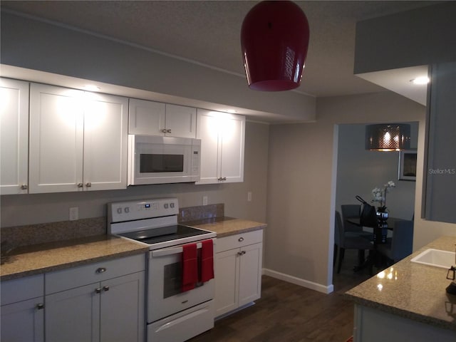 943 Millenbeck Ave, Deltona, FL 32725 - kitchen featuring white appliances, baseboards, dark wood finished floors, and white cabinets